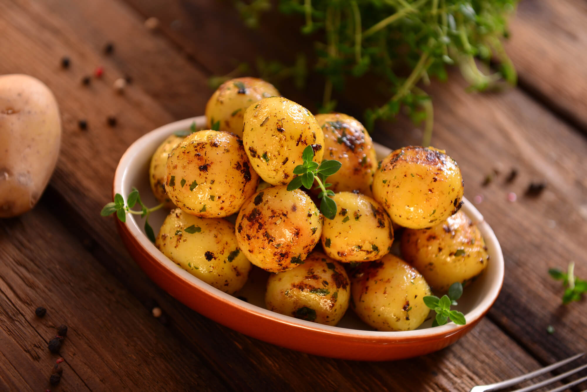 Cartofi copți în tavă la cuptor așezați într-o farfurie.