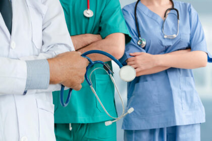 Grup de medici în halate și cu stetoscoape așteptând pe holul spitalului.