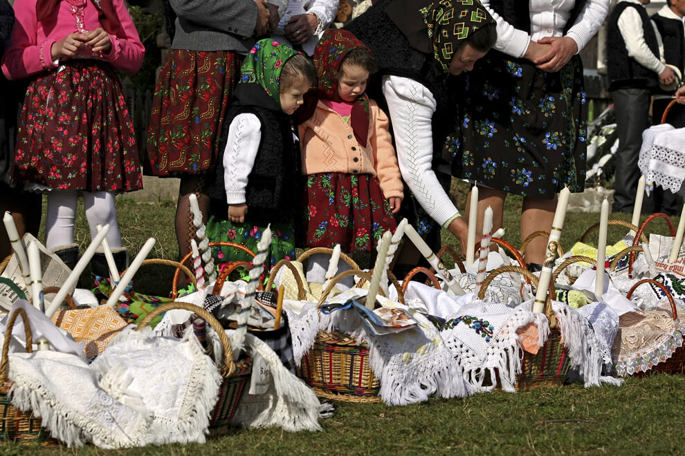 Copii în costume tradiționale lângă coșuri de Paște, în curtea bisericii din Maramureș