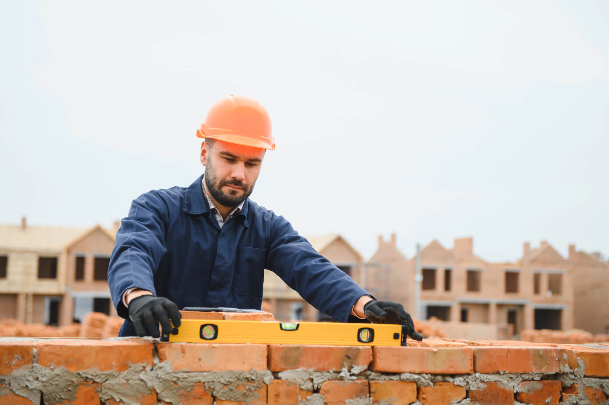 Muncitor pe un șantier zidește cărămizi la o construcție. Sectorul construcțiilor din România este în cea mai mare creștere. Record în Europa.
