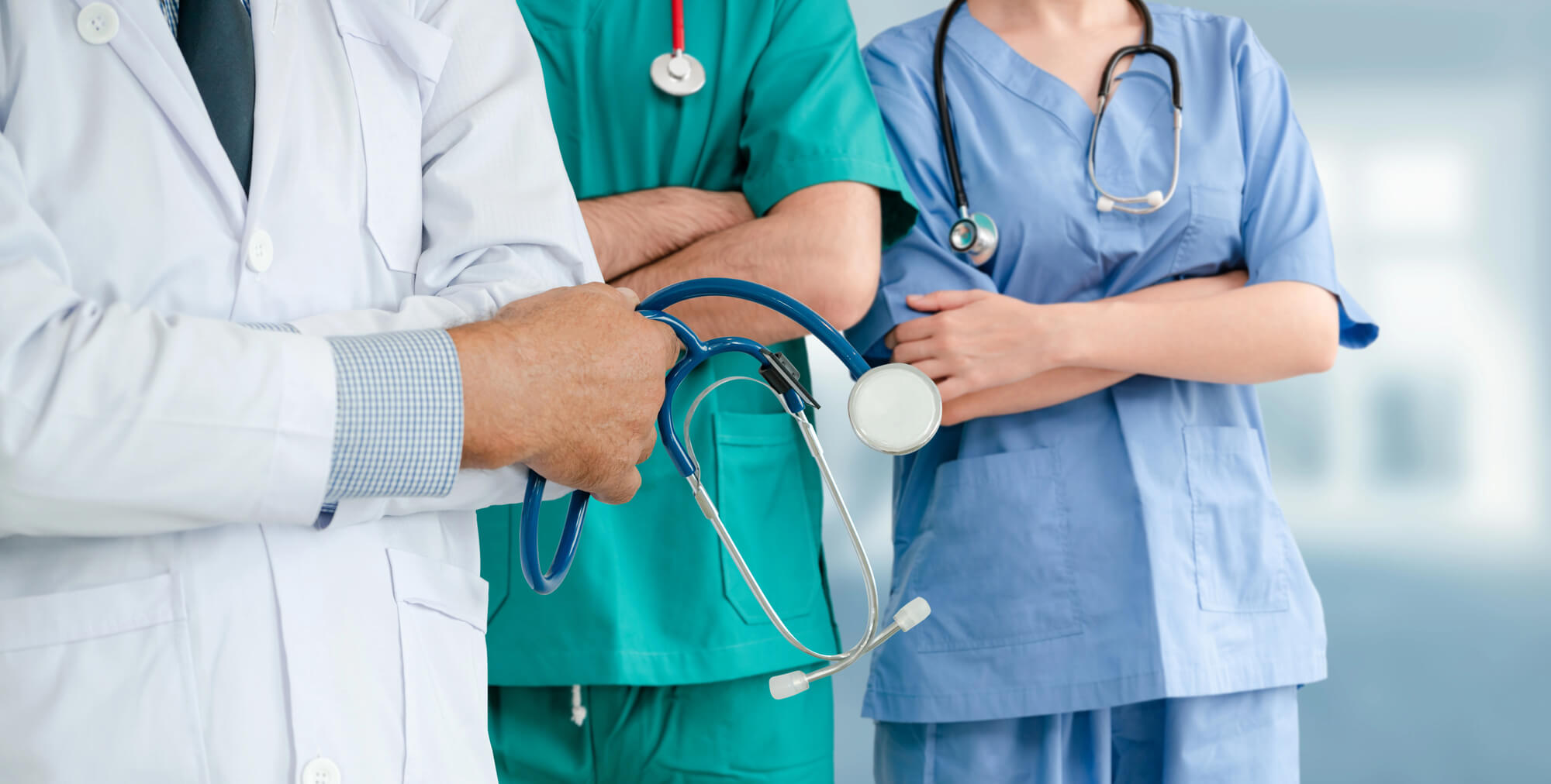 Grup de medici în halate și cu stetoscoape așteptând pe holul spitalului.