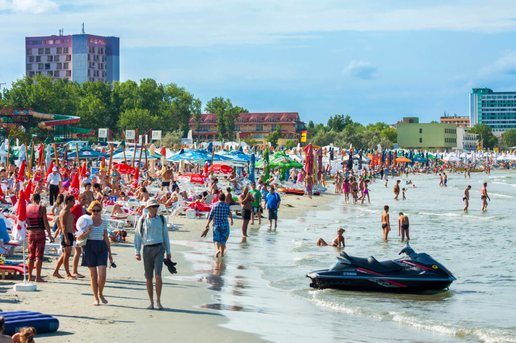 plajă aglomerată în Mamaia cu turiști și hoteluri pe litoralul românesc