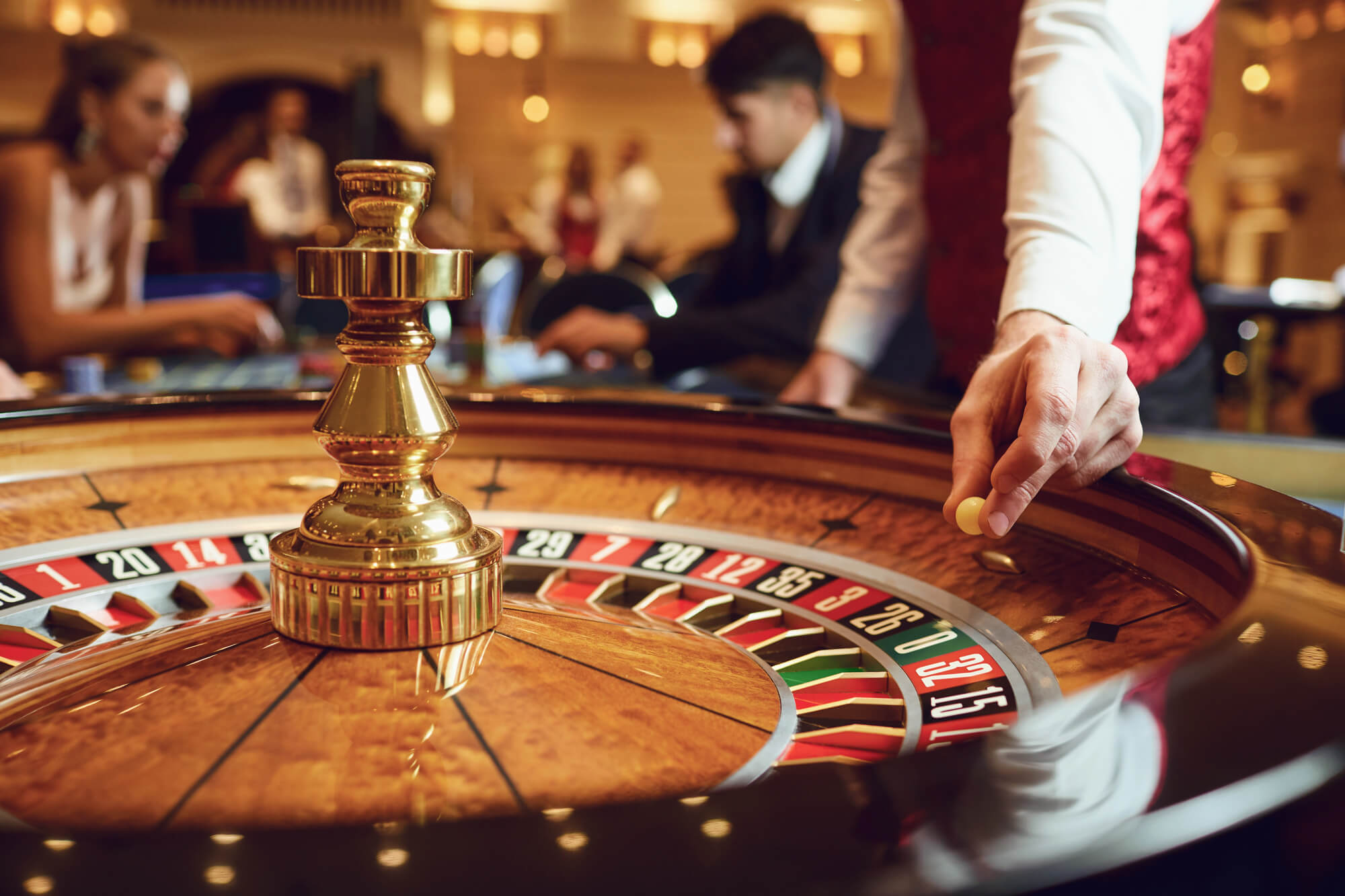 ruletă într-un casino cu crupier și jucători la masa de joc